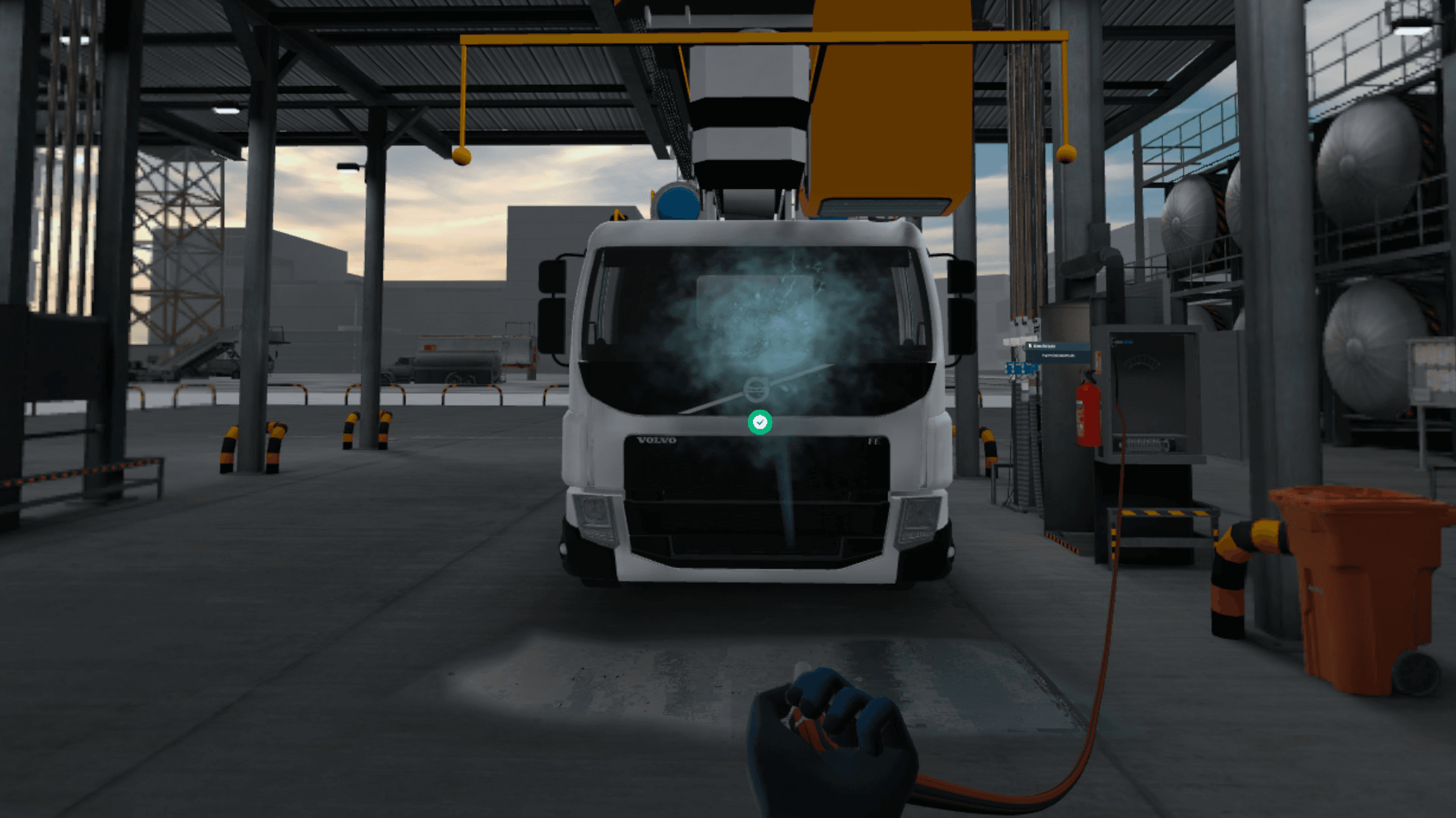 Une main gantée dirige un tuyau de lavage vers le pare-brise embué d'un camion de dégivrage sous un portique de service.