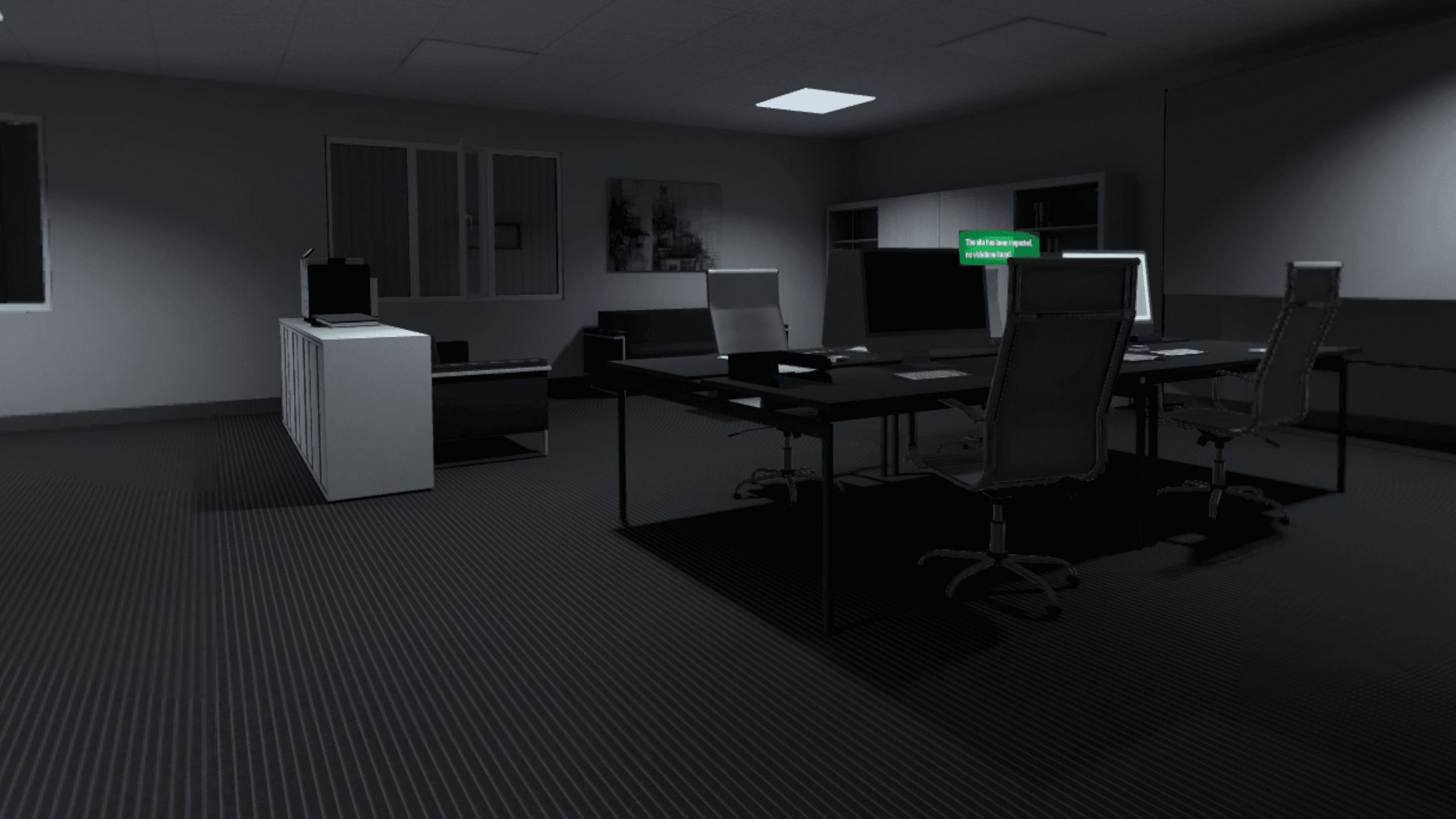 Un bureau paysager faiblement éclairé avec bureaux, écrans et chaises, un panneau au mur indiquant que le site a été inspecté sans infraction relevée.